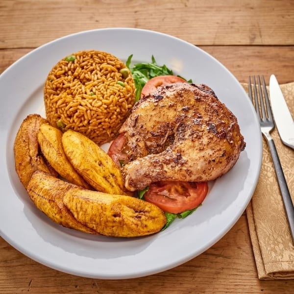 Roasted chicken leg, jollof rice, fried plantains, and salad on a white plate.